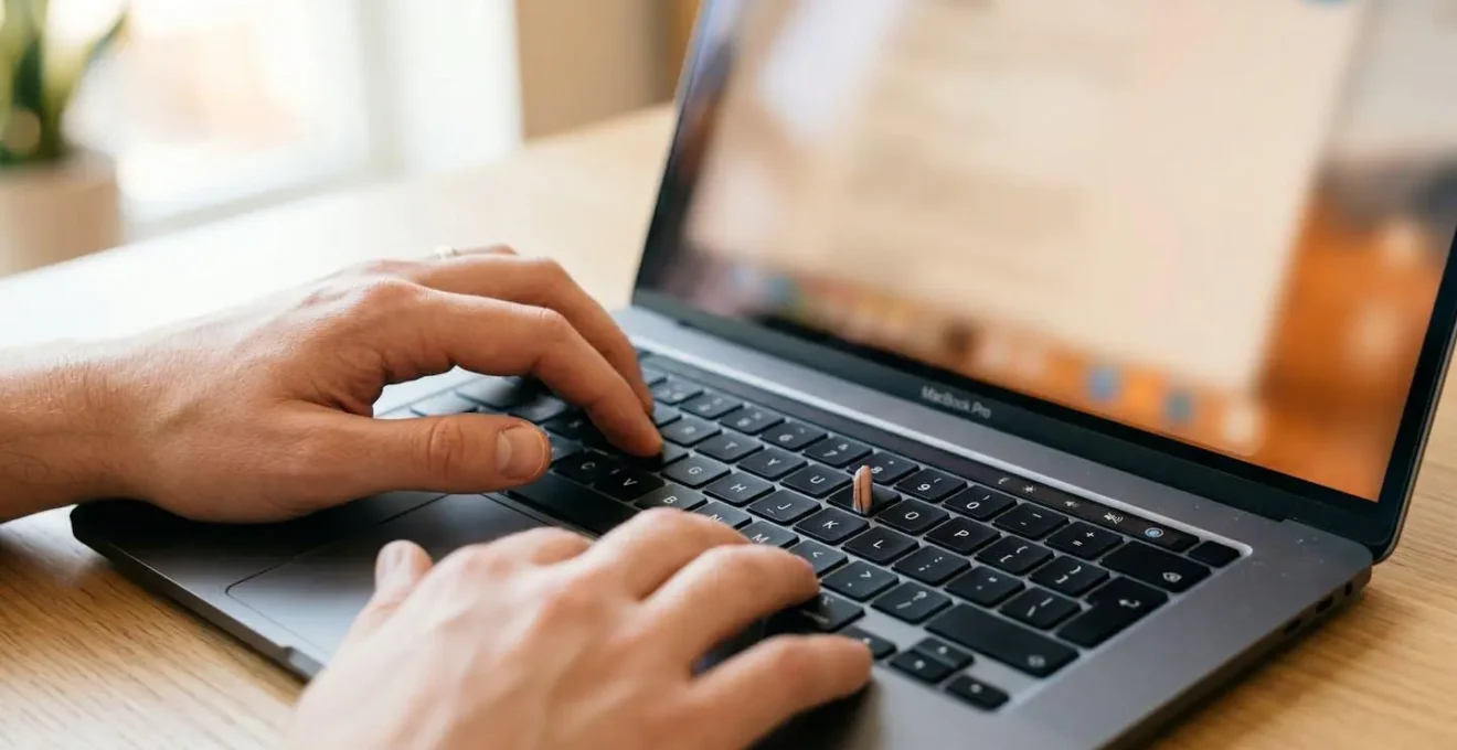 Gros plan sur des mains féminines tapant sur un clavier d'ordinateur portable moderne avec écran complètement flouté en arrière-plan